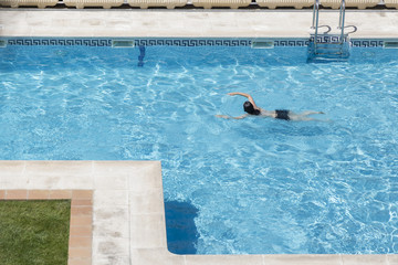 woman swimming in a blue pool outdoor
