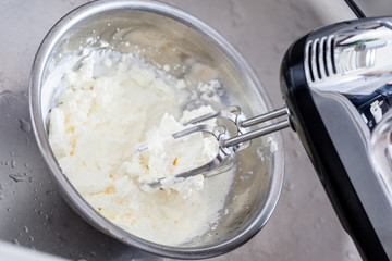 エプロンを着た女性、ハンドミキサー、ボウル