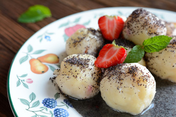 Sweet boiled dumplings filled with strawberries with a poppy seed sauce