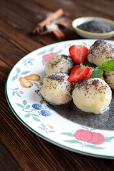 Sweet boiled dumplings filled with strawberries with a poppy seed sauce