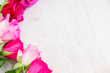 Fototapeta na wymiar Pink fresh roses close up border on white wooden background