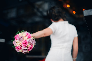 Wedding bouquet of pink, violet and white roses. Back of the bride in bokeh