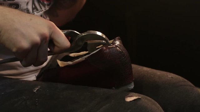 Shoemaker sews shoes. Hammering leather.