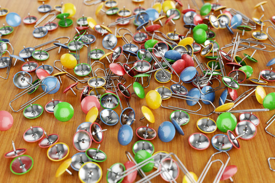 Office colored paper clips and drawing pins scattered on a table