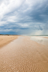 Sandy beach at the sea and storm clouds in the sky