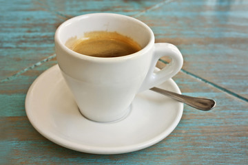 Photo of white cup of coffee on teal blue table