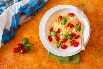 Farfalle pasta with cherry tomatoes and basil seen from above