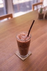 Glass of iced mocha milk coffee on wooden table, selective focus blurred effect for depth of field