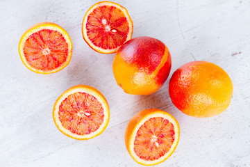 Mix of whole and cut red sicilian oranges with copy space on white wooden table