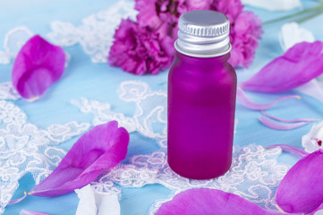 Pink bottle and petals on a blue background. Romantic beauty concept.