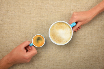 Two hands with espresso cappuccino coffee cups