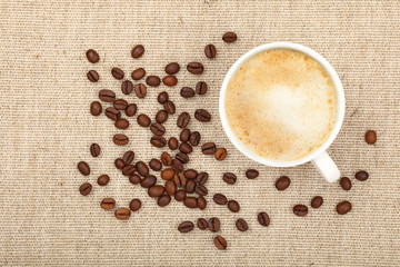 Latte cappuccino cup and coffee beans on canvas