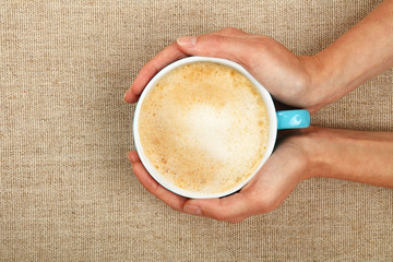 Two woman hands holding cappuccino coffee cup