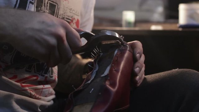 Shoemaker sews shoes. Hammering shoe leather