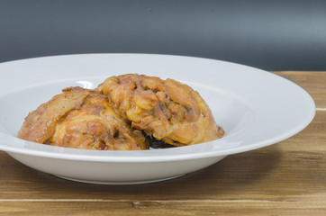 Roasted chicken with gravy in white plate on wood table