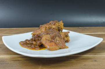 Roasted chicken with gravy in white plate on wood table