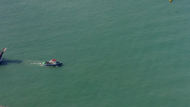 Tugboat towing an industrial barge across a main shipping channel, just off Hong Kong, China. Video 4k