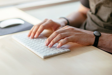 Young professional businessman working at his office computer. Close-up of male hands using modern computer at home, Home in the early morning, Shallow DOF.