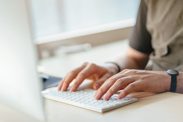 Close-up of male hands using computer at office, man's hands typing on keyboard in interior. Workplace in a skyscraper. Office in the early morning, Shallow DOF.