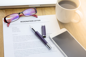 Businessman review his resignation letter on his desk before sending to his boss to quit his job with laptop computer and a cup of coffee.