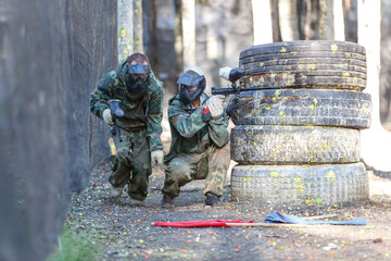 Two friends in extreme paintball training with capturing flags.