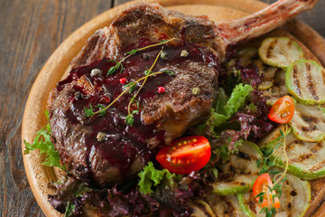 Grilled rib steak with red topping and squash on catering platter, closeup