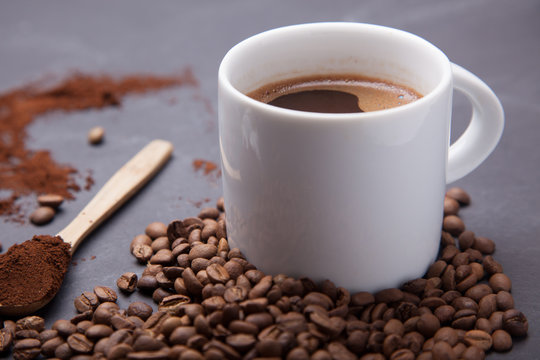 white cup and coffee beans on black