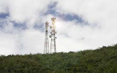 stanchion of Telecommunication mast TV antennas wireless technology on a hilltop of green mountain, blue sky and cloud in background,selective focus,light flare effect added