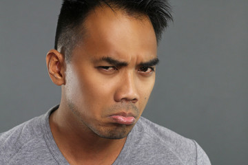 Grumpy young man over a gray background