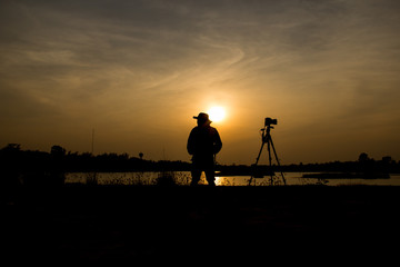 silhouette of photographer a lake on sunset.