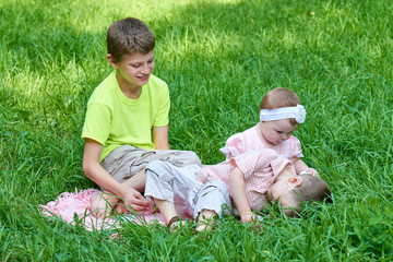 Three children sit in grass, playing and having fun.