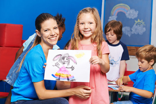 Mädchen zeigt gemaltes Bild im Kindergarten