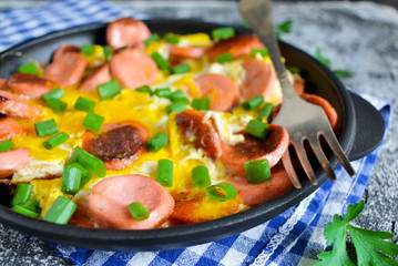 The dish for breakfast - scrambled eggs with sausage and green o