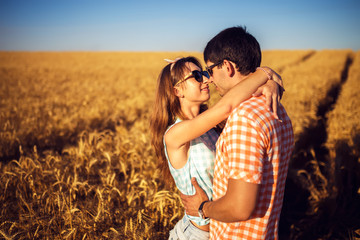 Couple in love enjoying tender moments during sunset . Emotional concept of relationship with travel boyfriend and girlfriends relaxing together. guys are walking in wheat
