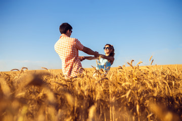 Couple in love enjoying tender moments during sunset . Emotional concept of relationship with travel boyfriend and girlfriends relaxing together. guys are walking in wheat 