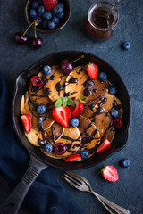 pancakes with fresh berries and chocolate sauce on pan, black ba