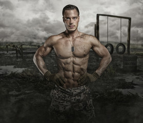 Shirtless muscular soldier in a training swampland.