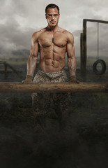 Shirtless male with wooden timber in a swampland.