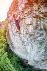 male rock climber. rock climber climbs on a rocky wall. climber threading the rope in quickdraw