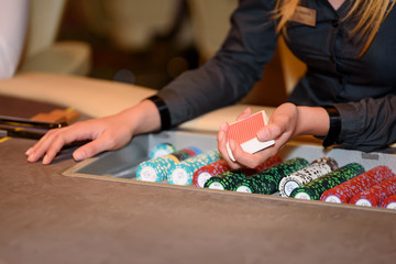 Closeup of hands of poker dealer with chips in casino, selective