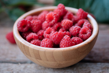 Fresh organic raspberries in bowl wood background.