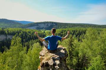 Man sitting on the top of the mountain in yoga pose