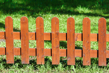 Wooden fence on green grass under the sun