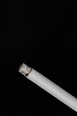 Burning cigarette with smoke on black background