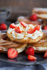 Cream puff rings decorated with fresh strawberry and caramel sau