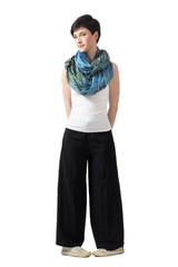 Fototapeta premium Shy bashful young short hair woman in wide pants in awkward leg pose. Full body length portrait isolated over white studio background.