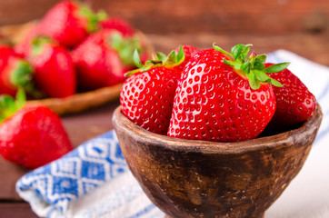 Ripe fresh juicy organic strawberries in old clay bowl