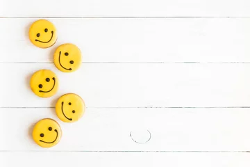 Poster Smiley faces on wooden white background. Food. Glazed cookies. Top view, flat lay © Flaffy