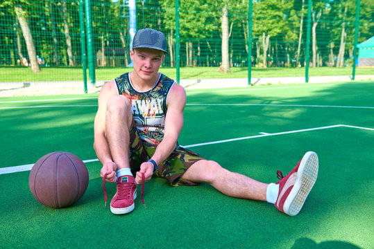 Man tying shoelaces relying on basketball ball