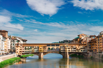 Fototapeta na wymiar famous bridge Ponte Vecchio over waters of river Arno with cloudy sky, Florence, Italy